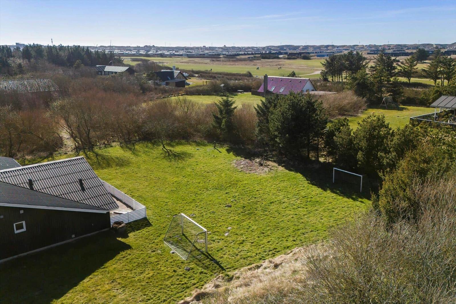 Grüner Garten mit Fußballtor und Blick auf Wohnhäuser und Felder.