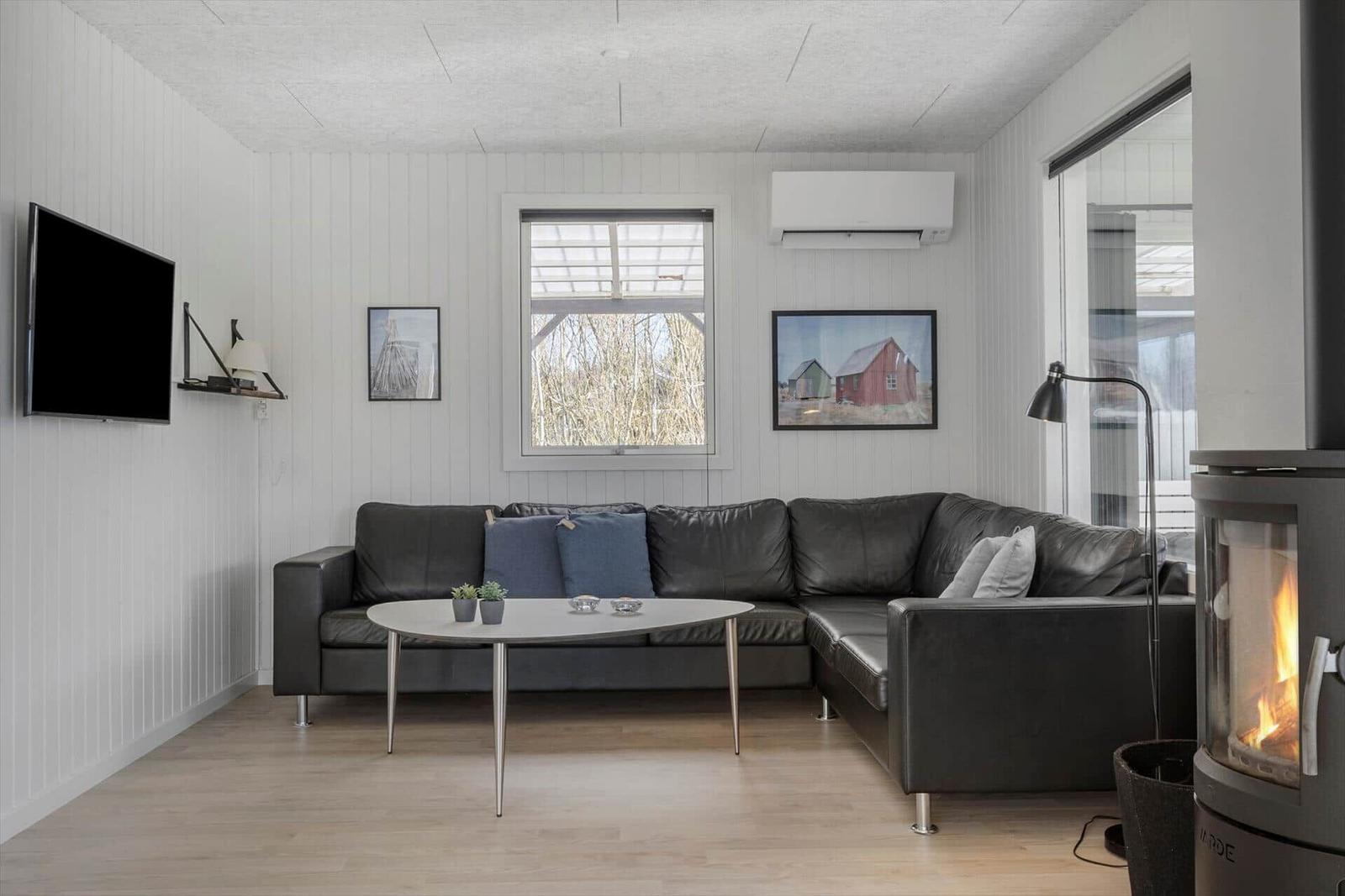 Wohnzimmer mit Sofa, Kamin und TV an der Wand.