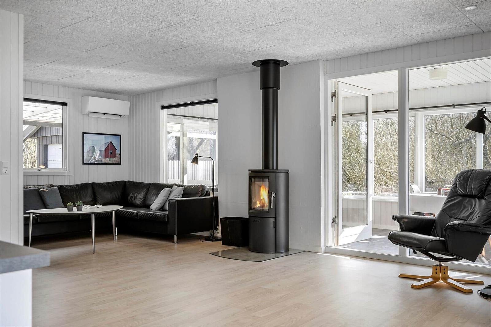 Wohnzimmer mit schwarzer Couch, Kamin und Terrassentür.