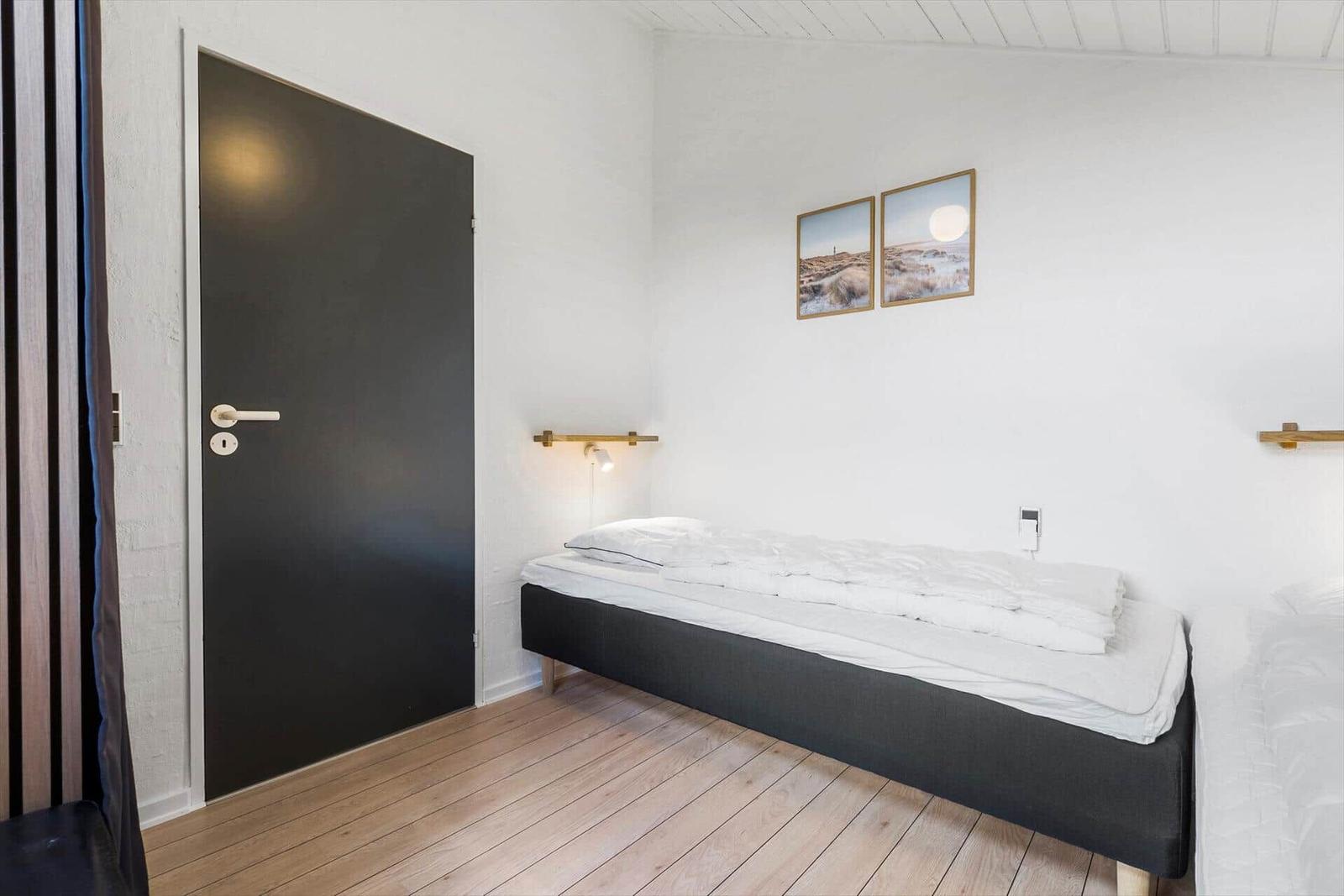 Schlafzimmer mit Bett, Wandbildern und Holzboden.