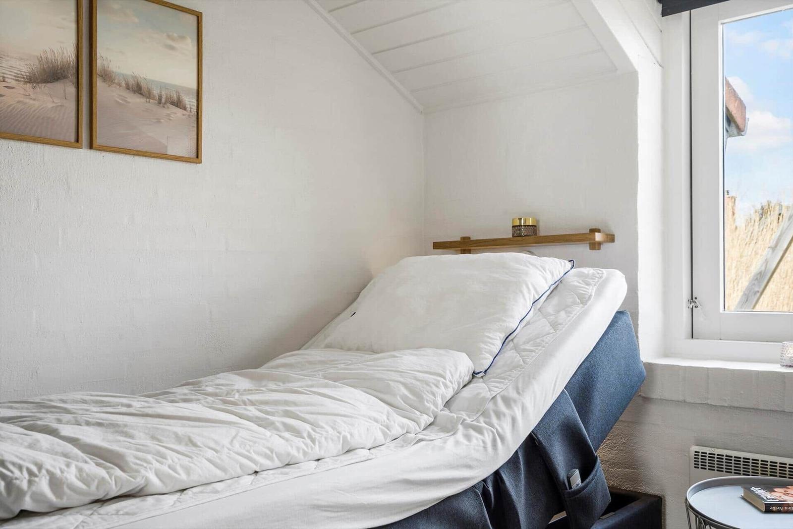 Schlafzimmer mit Bett, Fenster und Wandbildern.