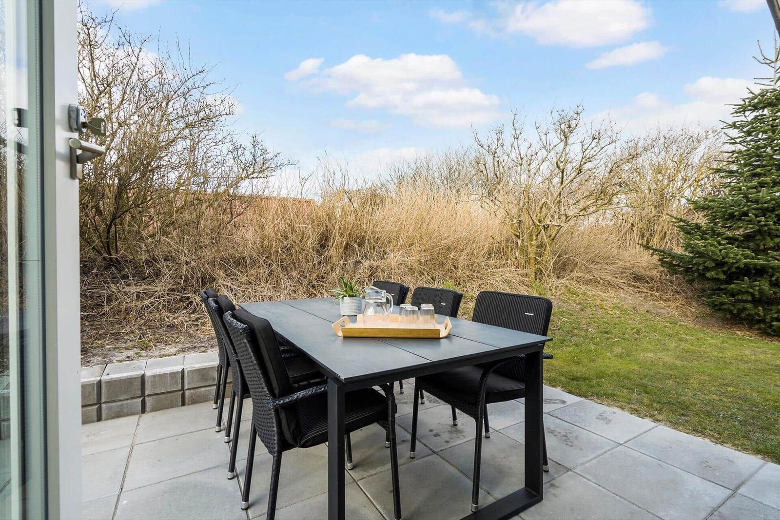 Terrasse mit Tisch und Stühlen, Blick auf Gras und Bäume