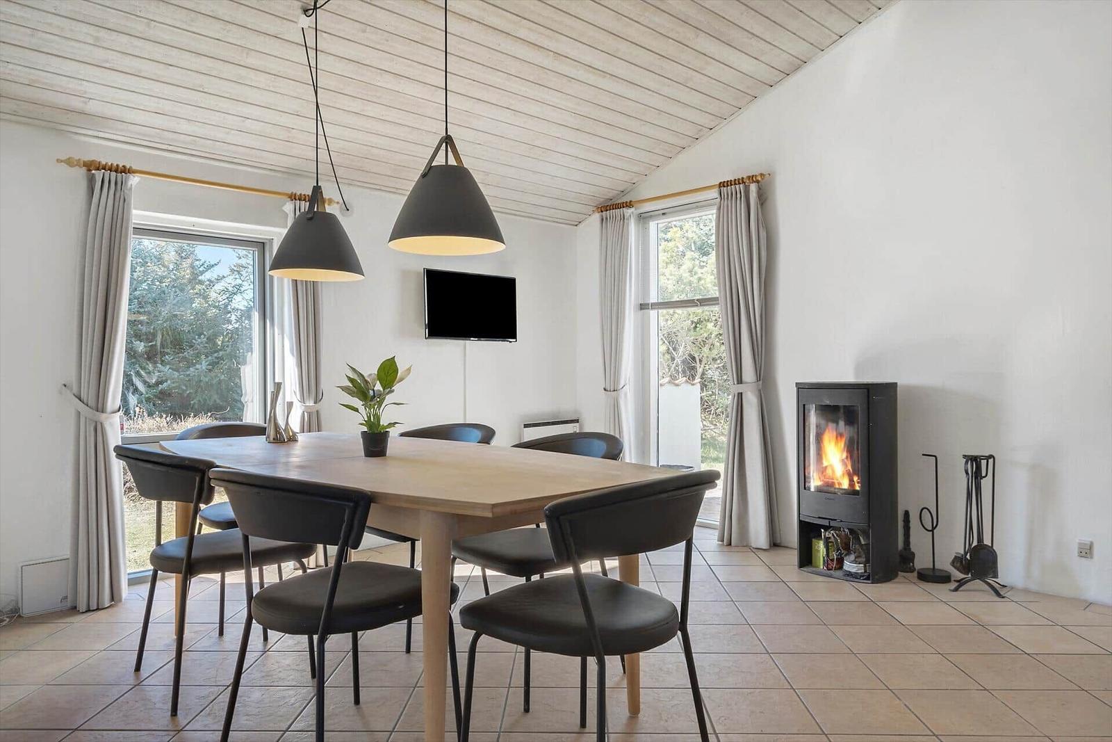 Esszimmer mit Holztisch, Stühlen, Kamin und Fenstern.