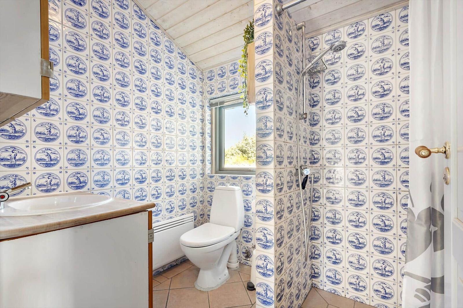 Badezimmer mit blau-weißen Fliesen, Toilette, Dusche und Waschbecken.