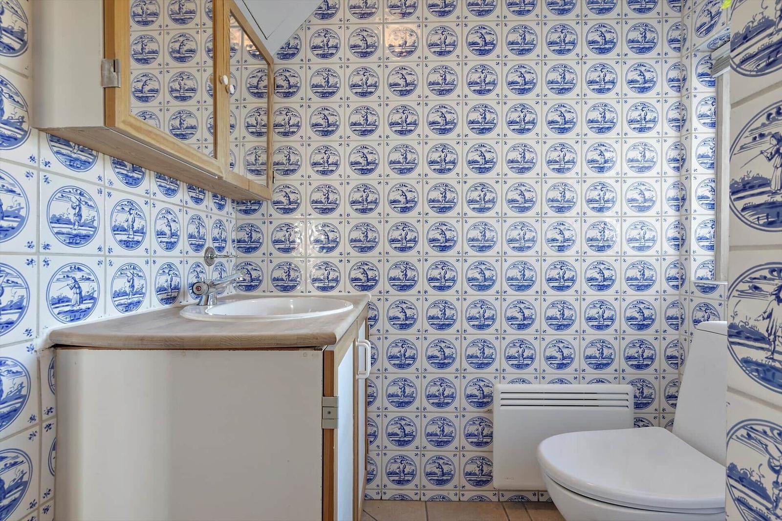 Badezimmer mit blau-weißen Fliesen, Waschbecken und Toilette.