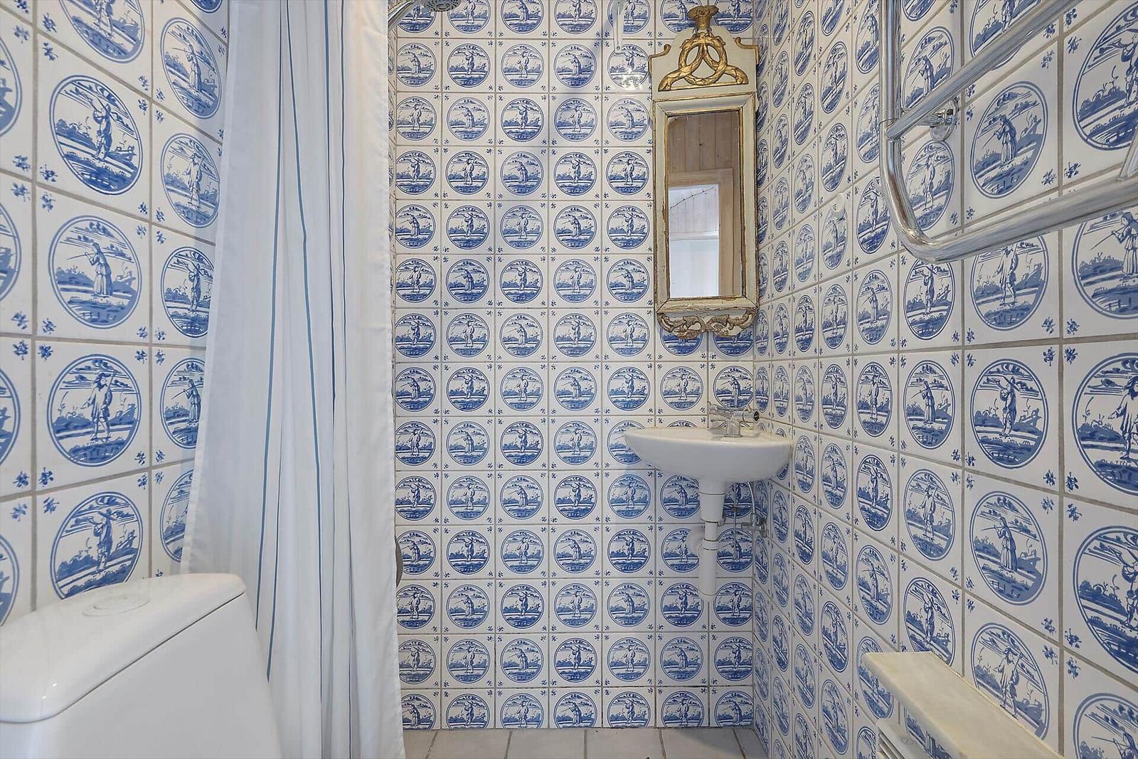 Badezimmer mit blau-weißen Fliesen, Waschbecken und Spiegel.