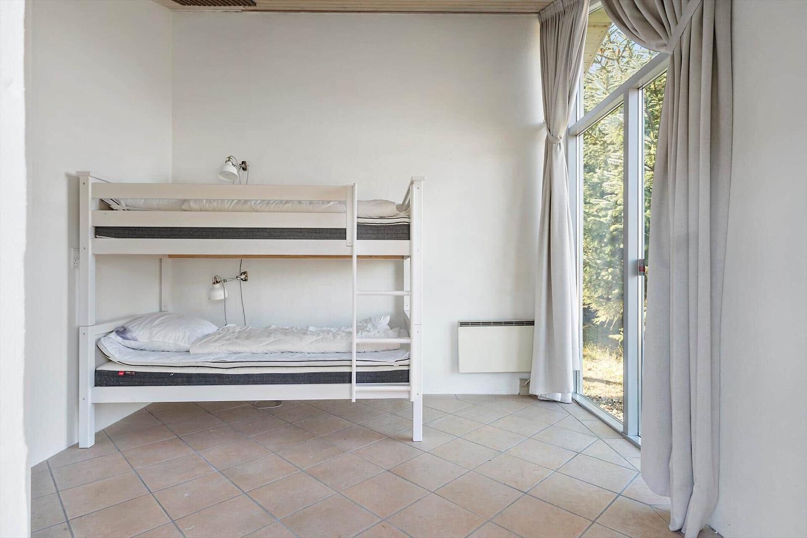 Zimmer mit Doppelstockbett, Fenster und Heizung.