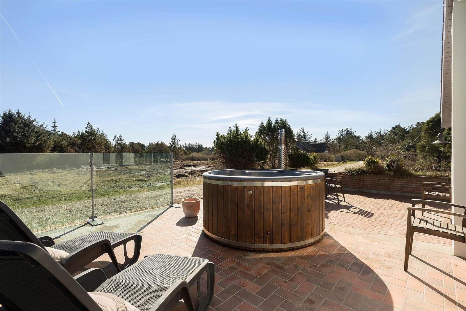 Terrasse mit Whirlpool, Liegen und Blick auf Wald