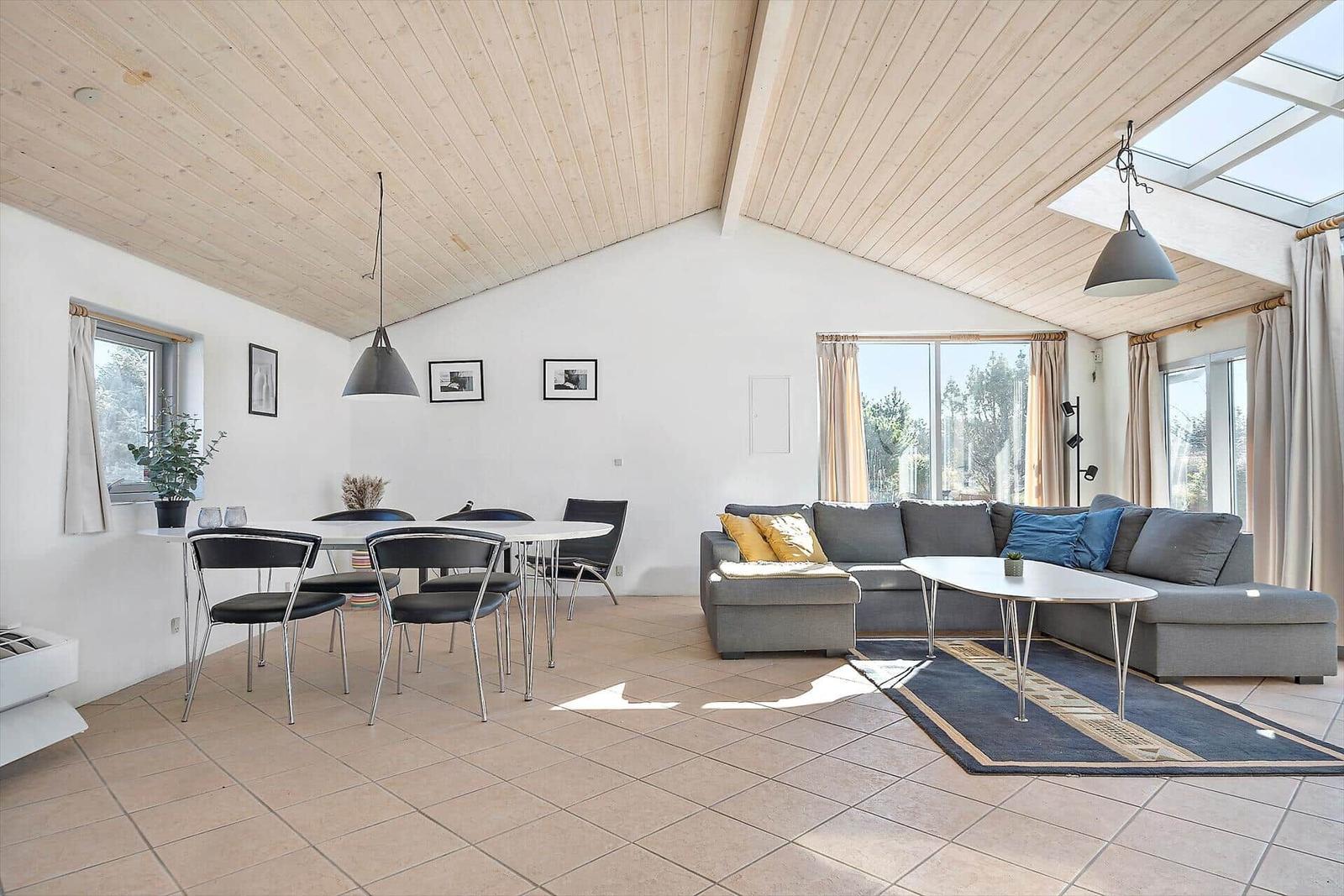 Wohn- und Essbereich mit Sofa, Tisch und Stühlen unter Holzdecke.