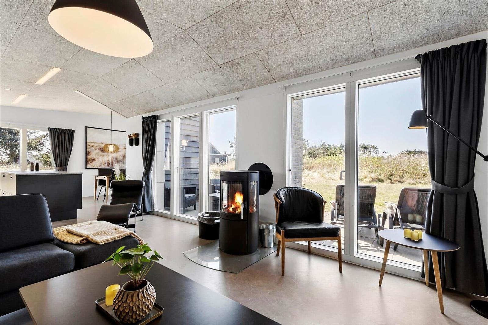 Wohnraum mit Kamin, Sitzgelegenheiten und Blick auf die Terrasse.