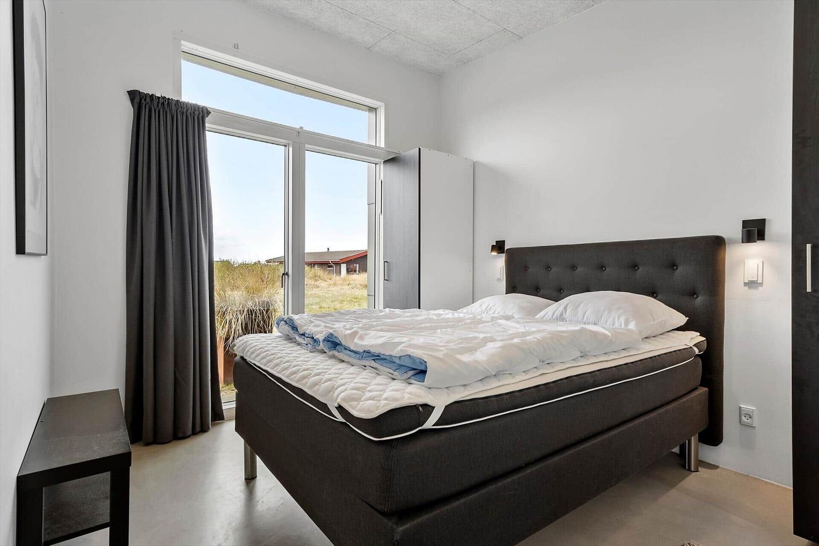 Schlafzimmer mit Bett, Fenster und Gardinen