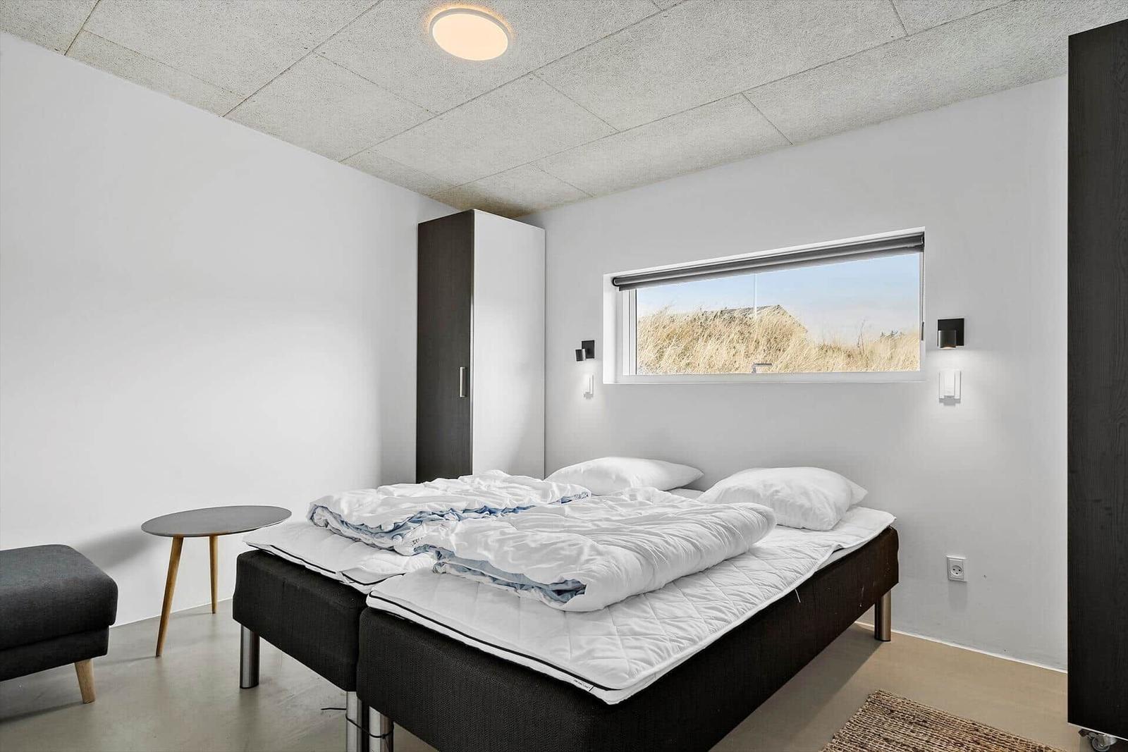 Schlafzimmer mit Bett, Schrank und Fenster zum Dach