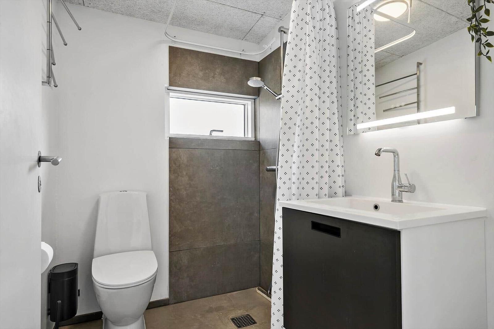 Badezimmer mit Toilette, Dusche und Waschbecken mit Spiegel.
