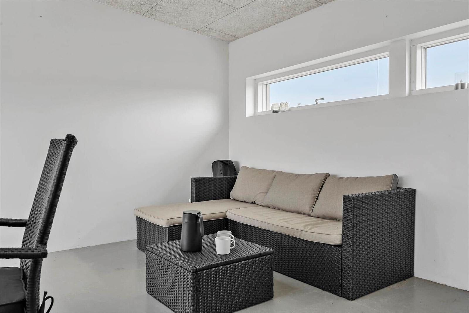 Terrassenbereich mit Sofa, Sitzbank und Tisch. Fenster mit Blick nach draußen.