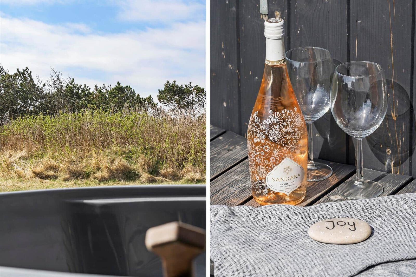 Blick auf Grasland und Bäume. Eine Flasche Rosé und zwei Gläser auf einer Terrasse.