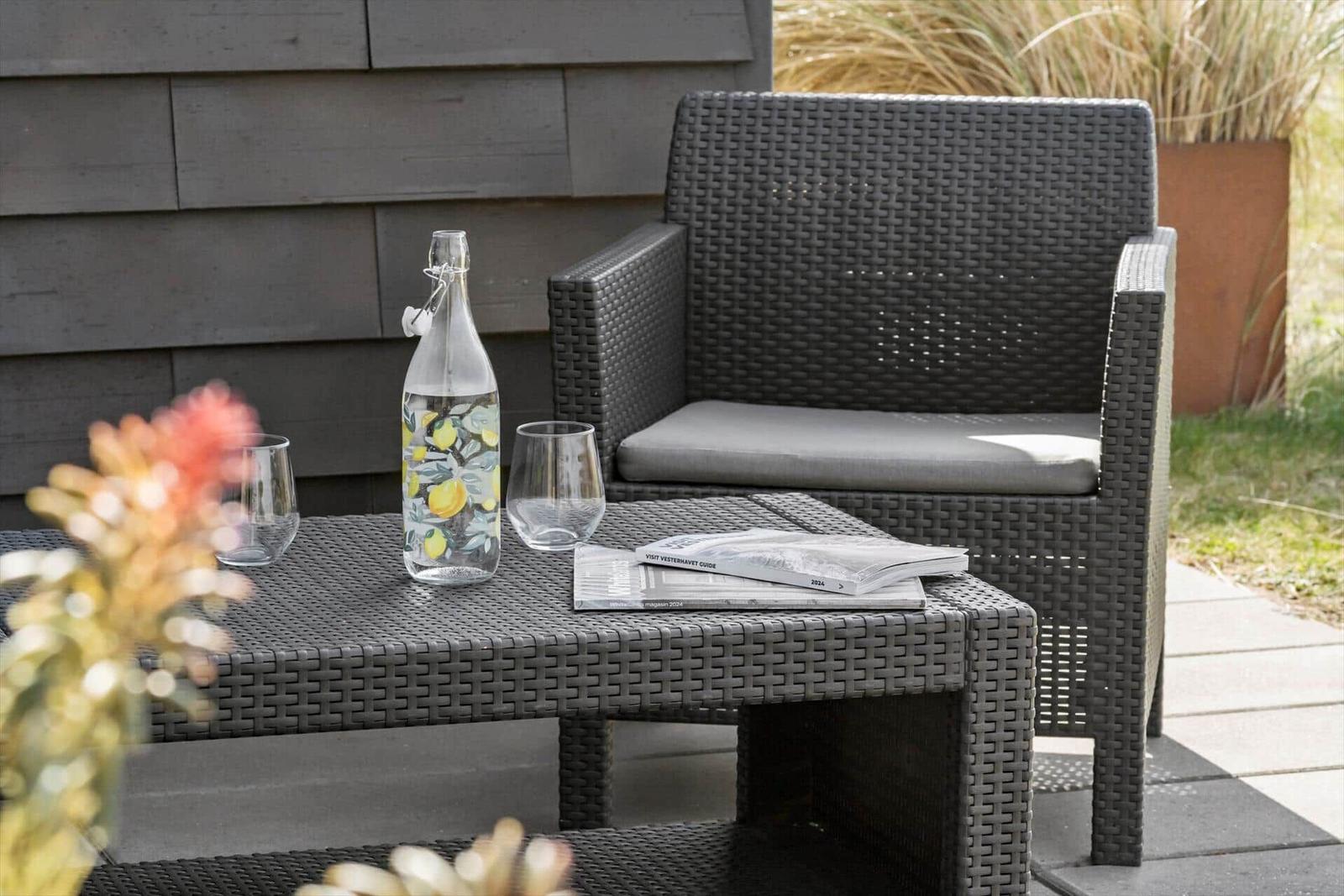 Außentisch mit Stuhl, Wasserflasche und Broschüren auf Terrasse