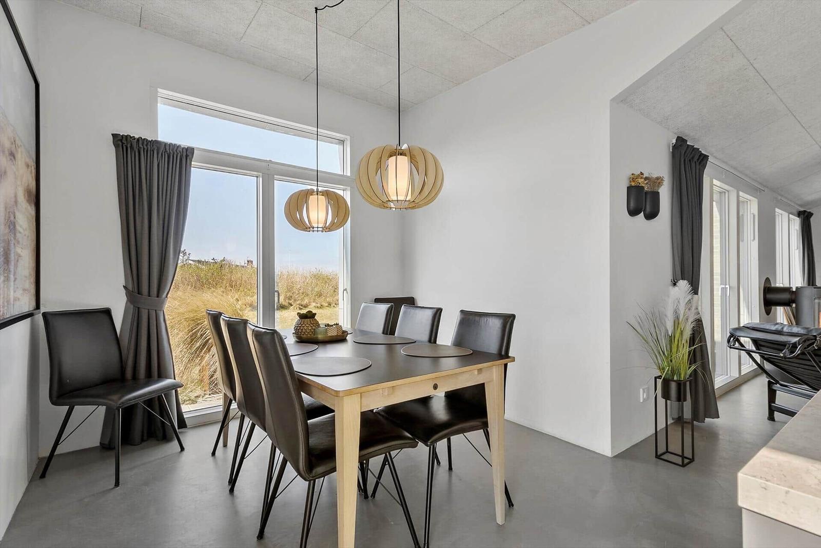 Esszimmer mit Tisch, Stühlen und Fensterblick auf Grasland.