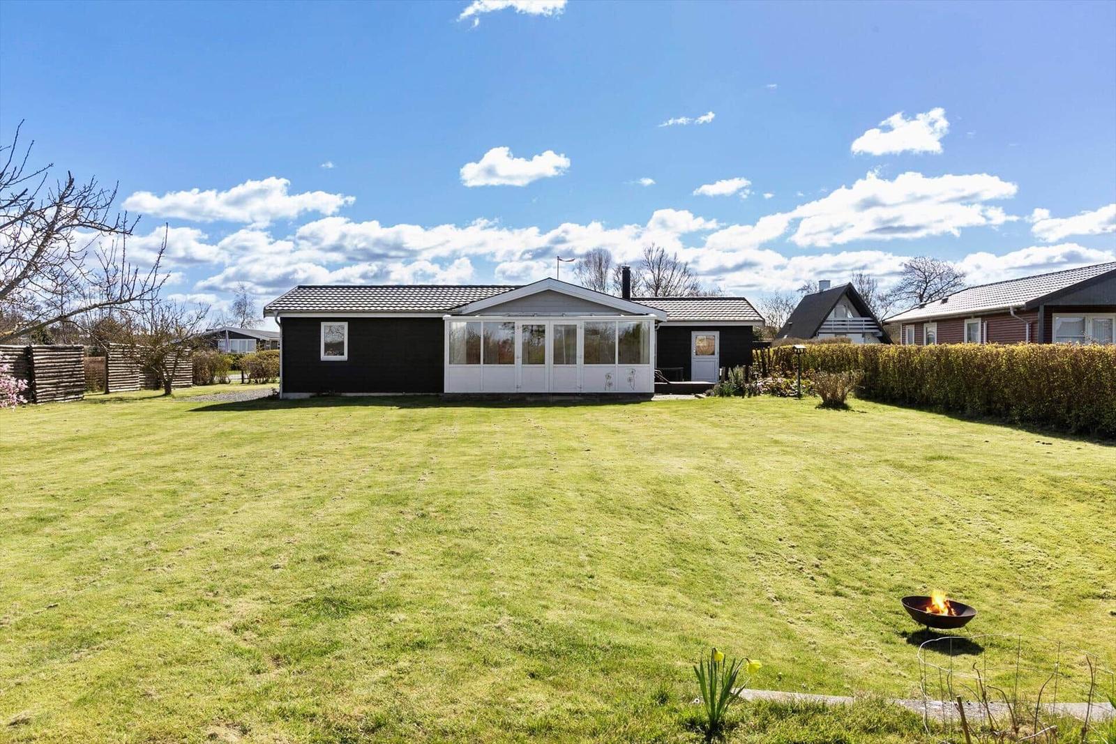 Schwarzes Haus mit weißem Anbau und Garten mit Feuerkorb.
