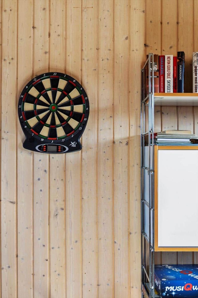 Dartboard an Holzwand, Bücherregal daneben