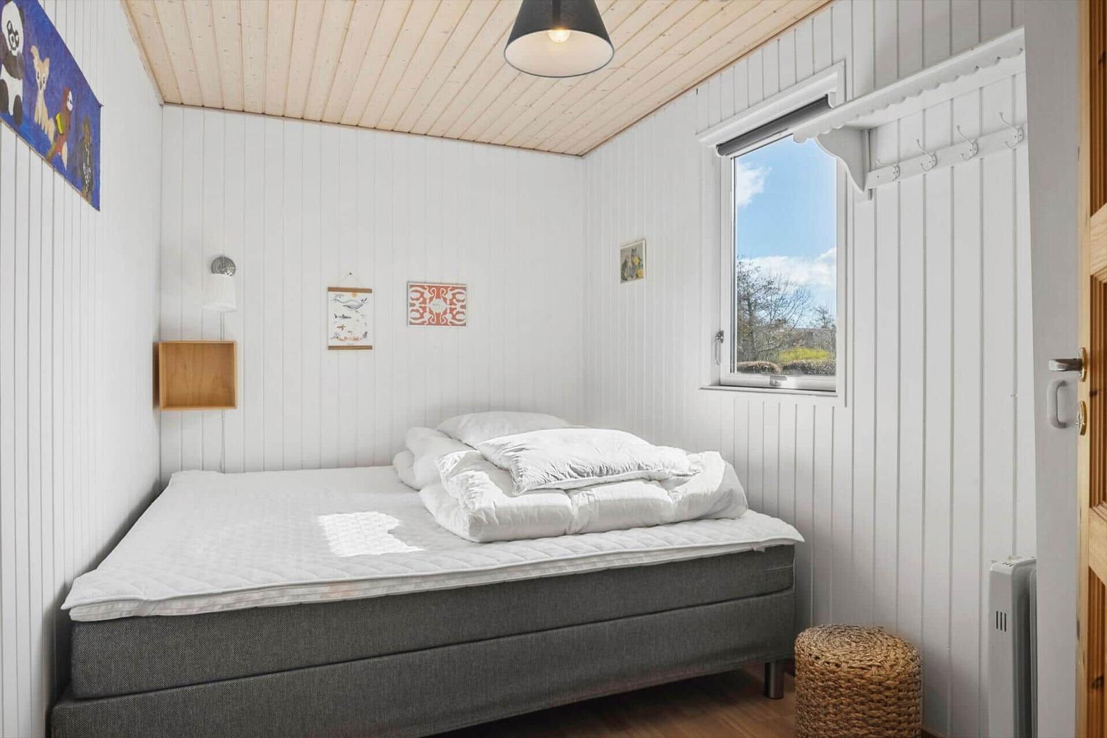 Schlafzimmer mit Bett, Fenster und Wanddekoration.