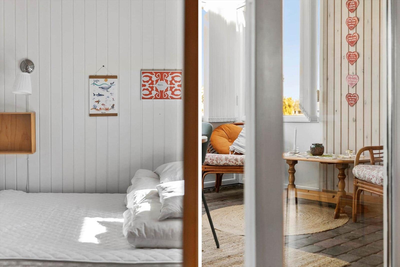 Schlafzimmer mit Bett und Wandbildern. Nebenraum mit Tisch, Stühlen und Fenster.