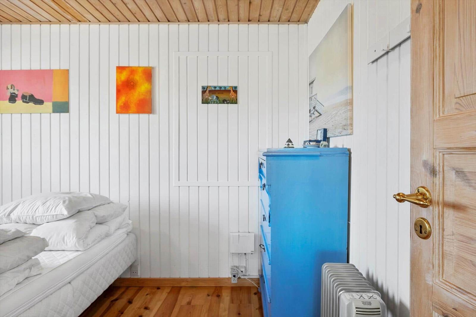 Schlafzimmer mit weißer Wand, blauem Schrank und Holzboden.