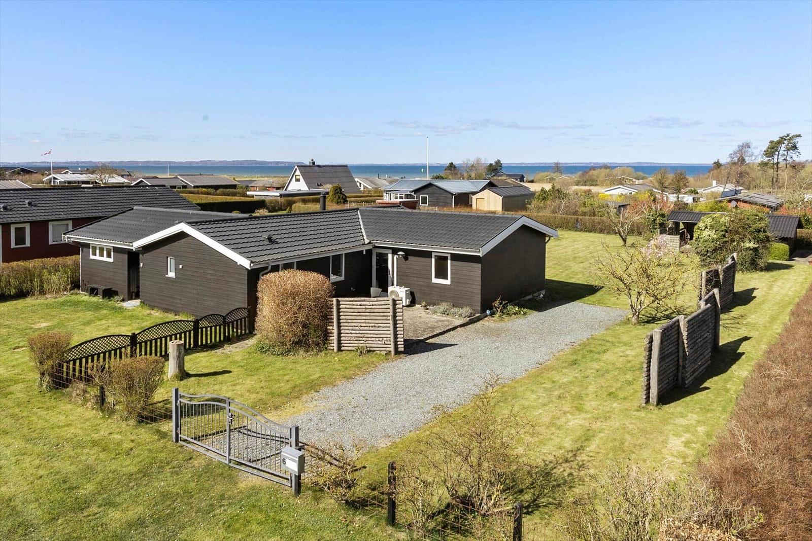 Ein dunkelbraunes Haus mit Garten und Blick aufs Meer.