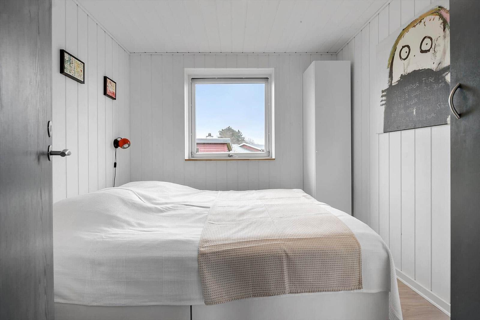 Bedroom with white bedding, window, and wall art.