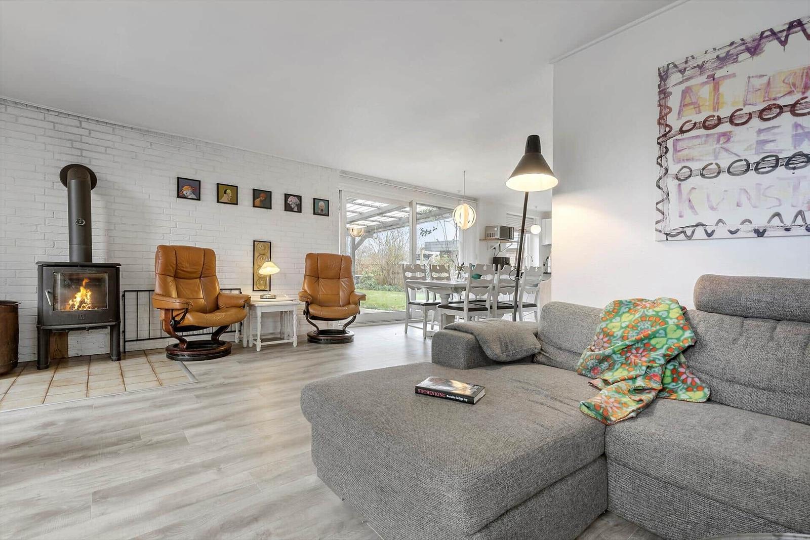 Living room with fireplace, leather chairs, and sofa. Access to terrace and dining area.