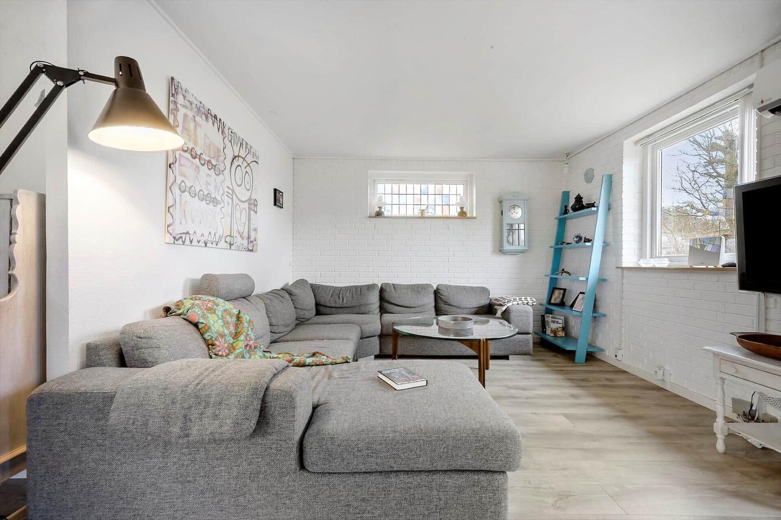 A living room with gray sofa, glass table, and blue shelf.