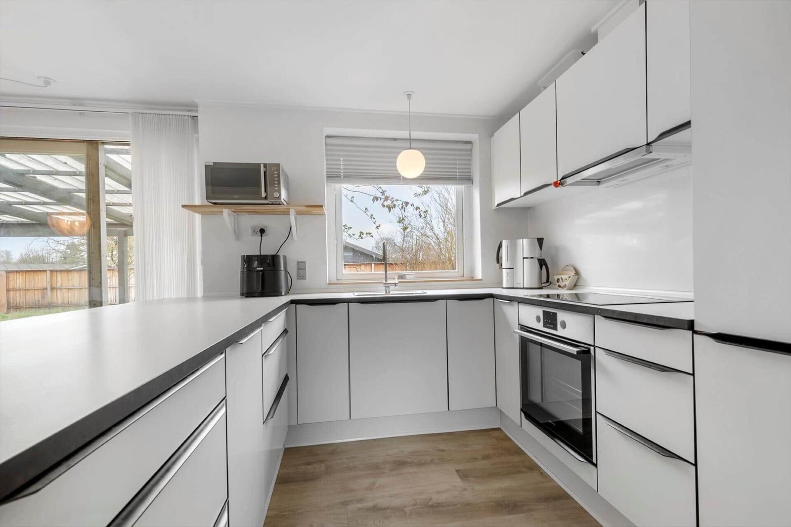 Kitchen with white cabinets, countertop, and window overlooking outside.