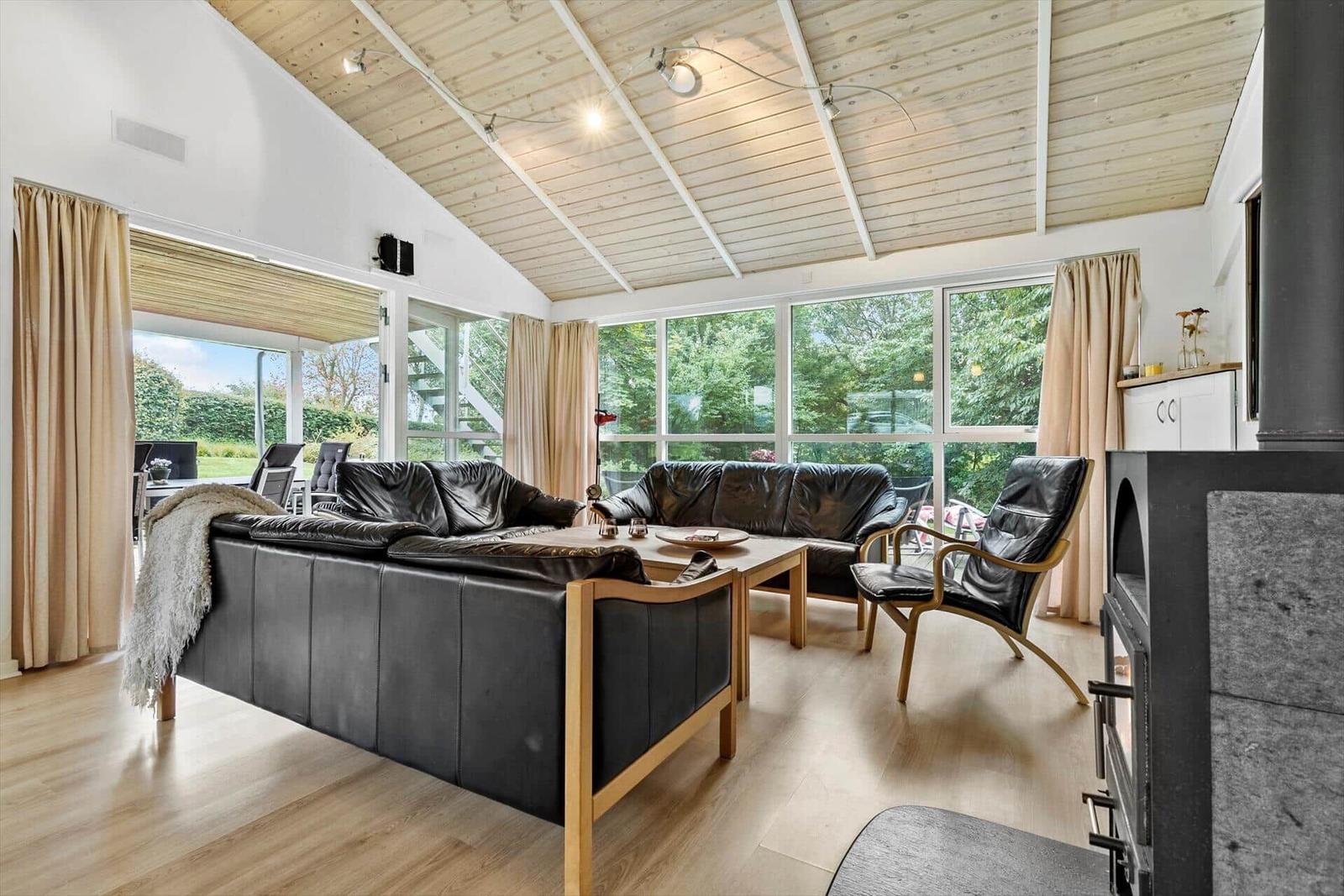 Wohnzimmer mit schwarzen Ledermöbeln, Holzboden und großem Fensterblick.