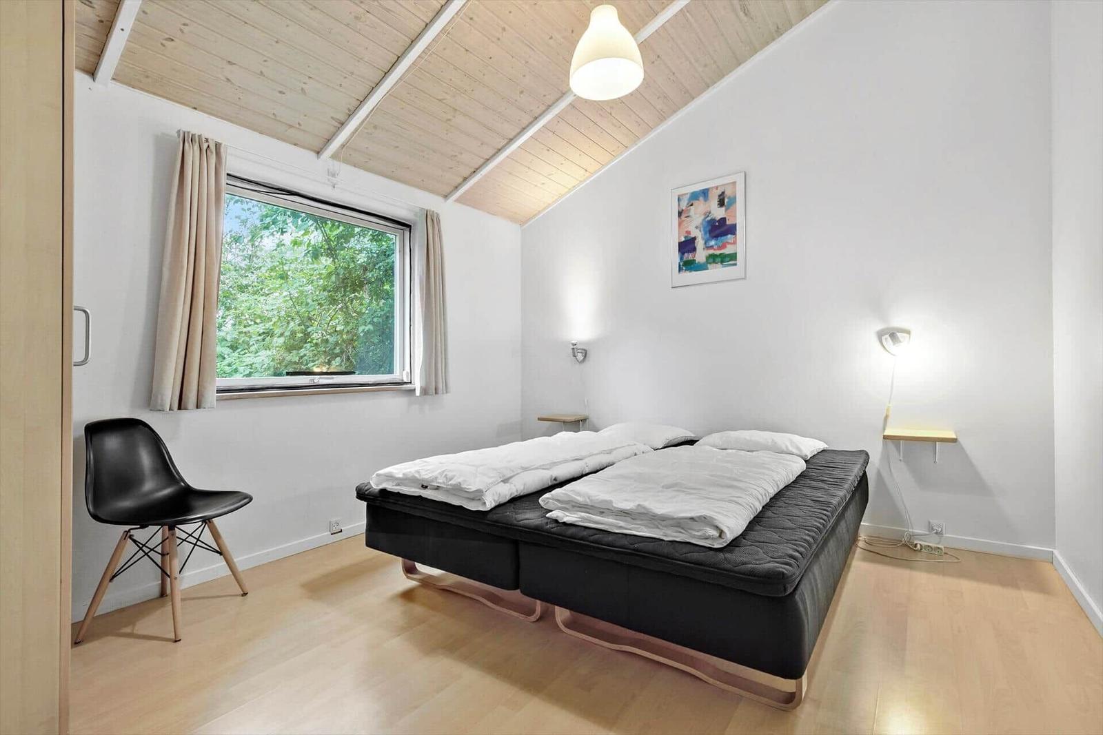 Schlafzimmer mit Bett, Fenster und Stuhl.