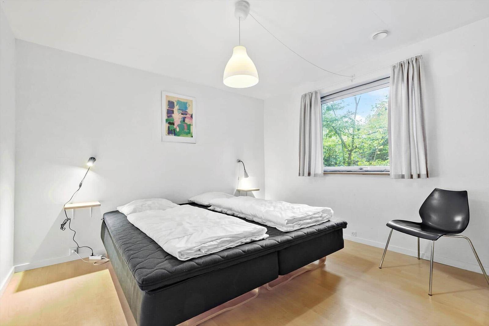 Schlafzimmer mit Doppelbett, Fenster und Stuhl.