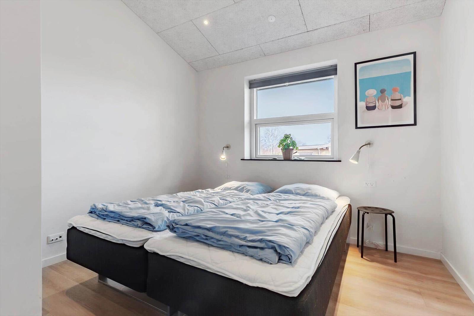 Schlafzimmer mit Doppelbett, Fenster und Bild an der Wand.