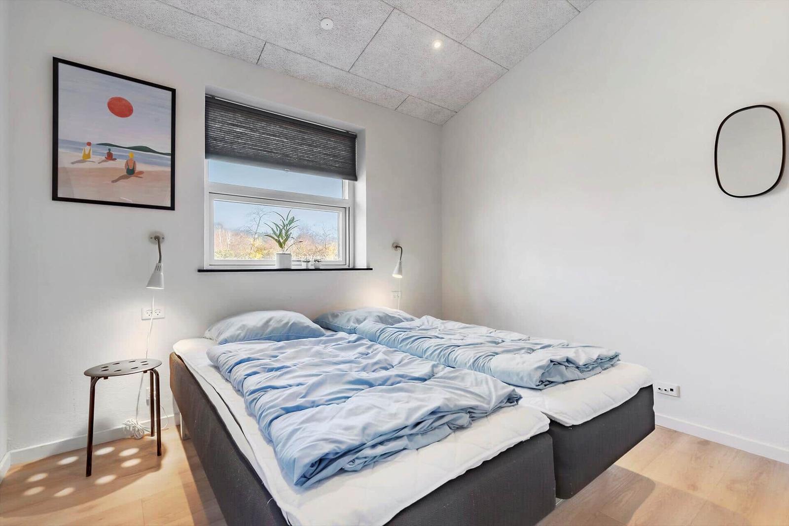Schlafzimmer mit Doppelbett, Fenster und Wandbild.