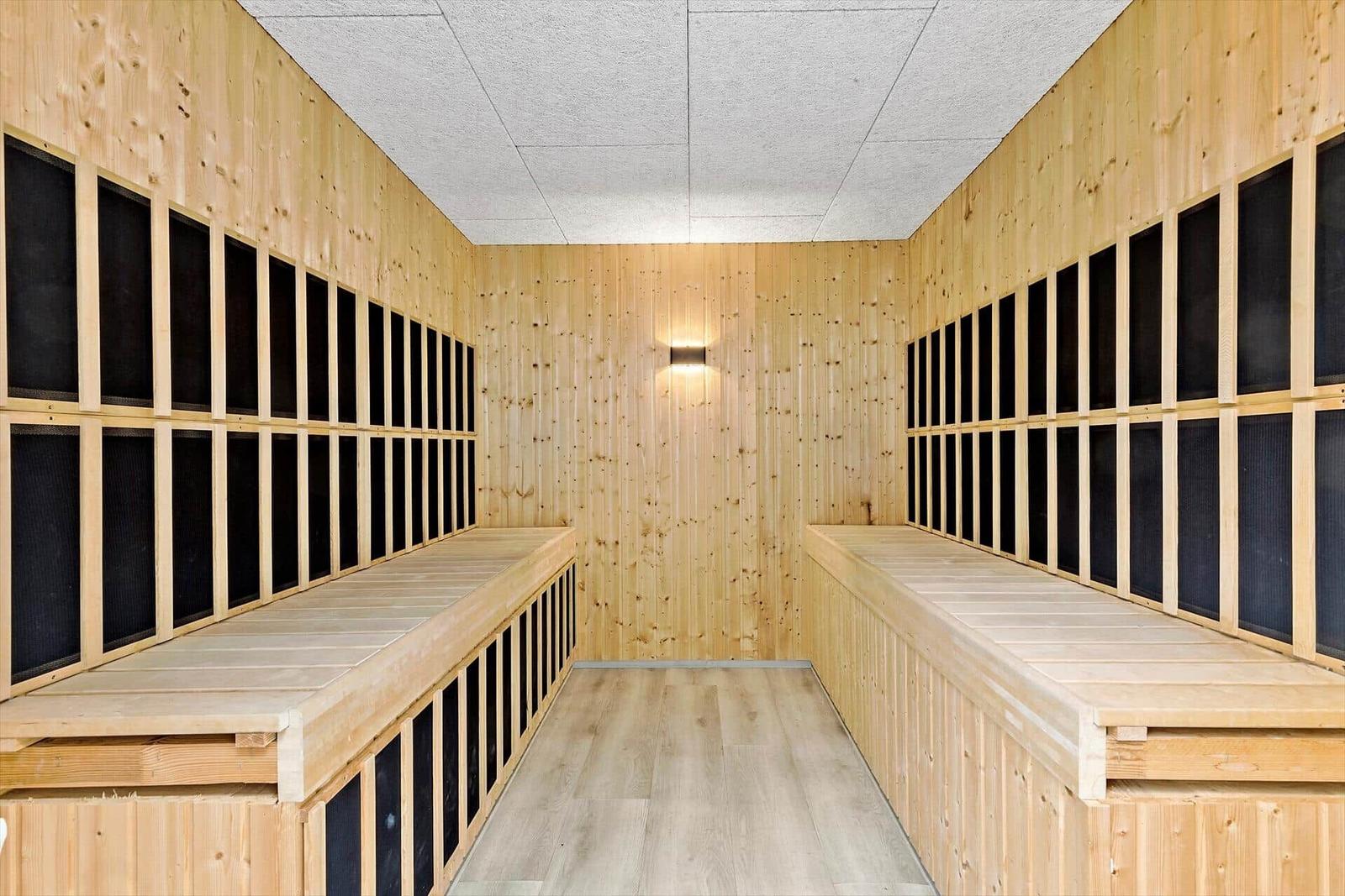 Sauna mit Holzwänden und Sitzbänken entlang der Wände.
