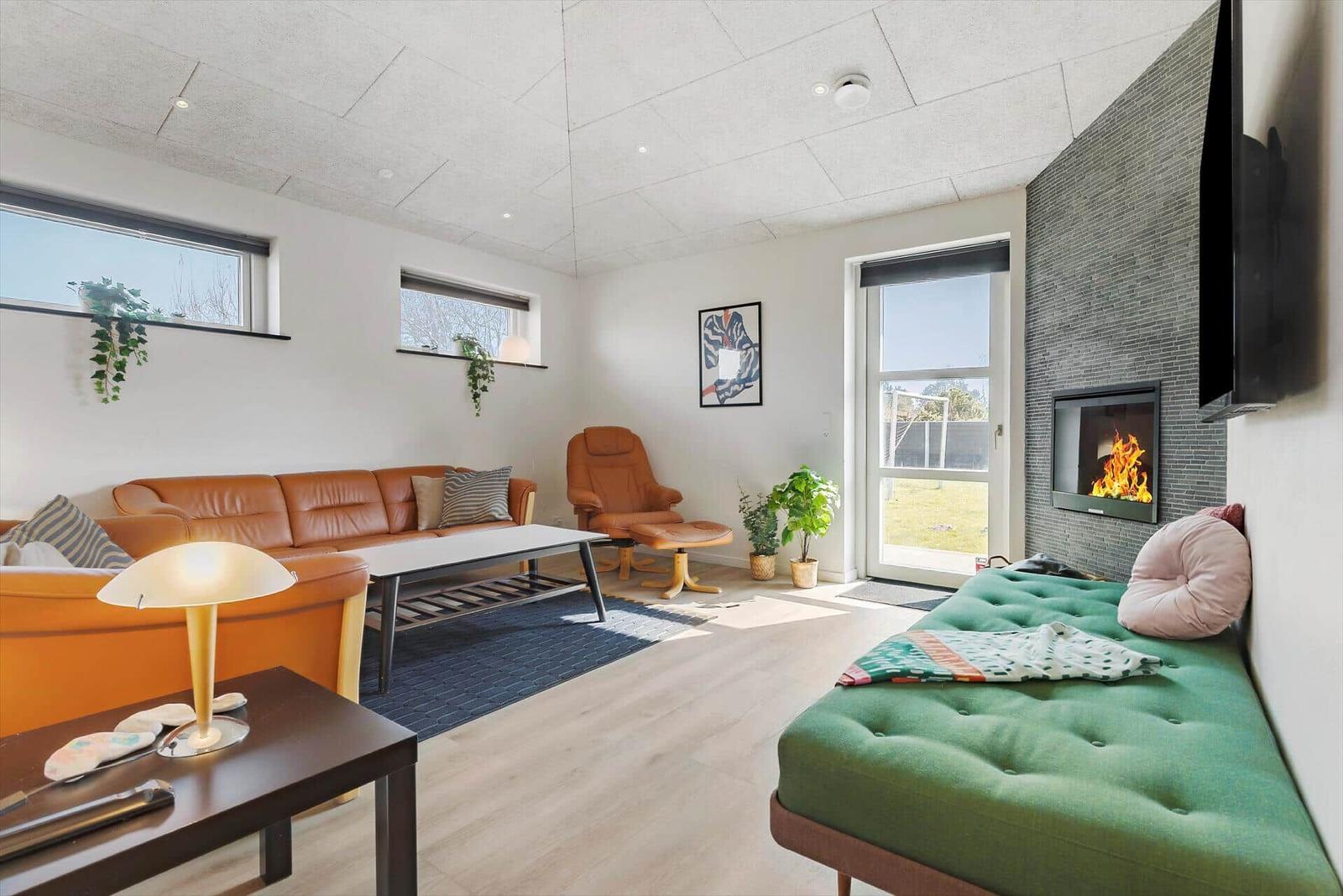 Wohnzimmer mit Sofa, Sessel, Kamin und grüner Schlafcouch.