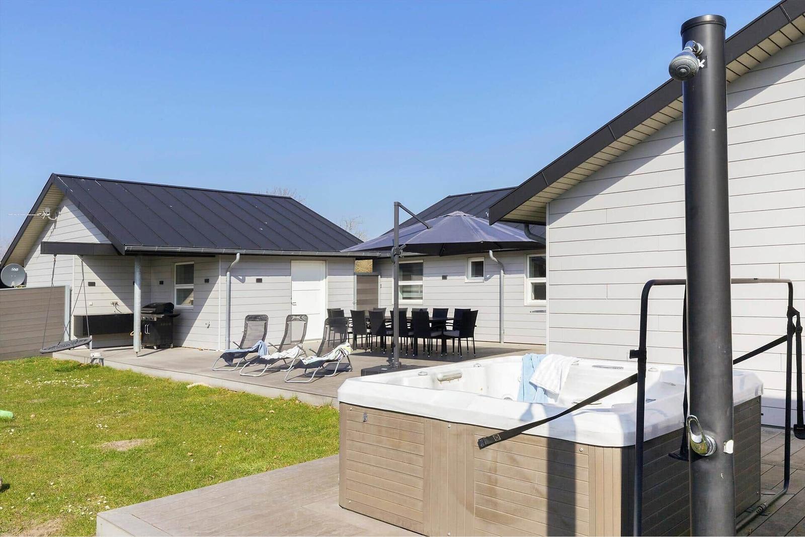 Außenbereich mit Whirlpool, Liegestühlen und Grillplatz.