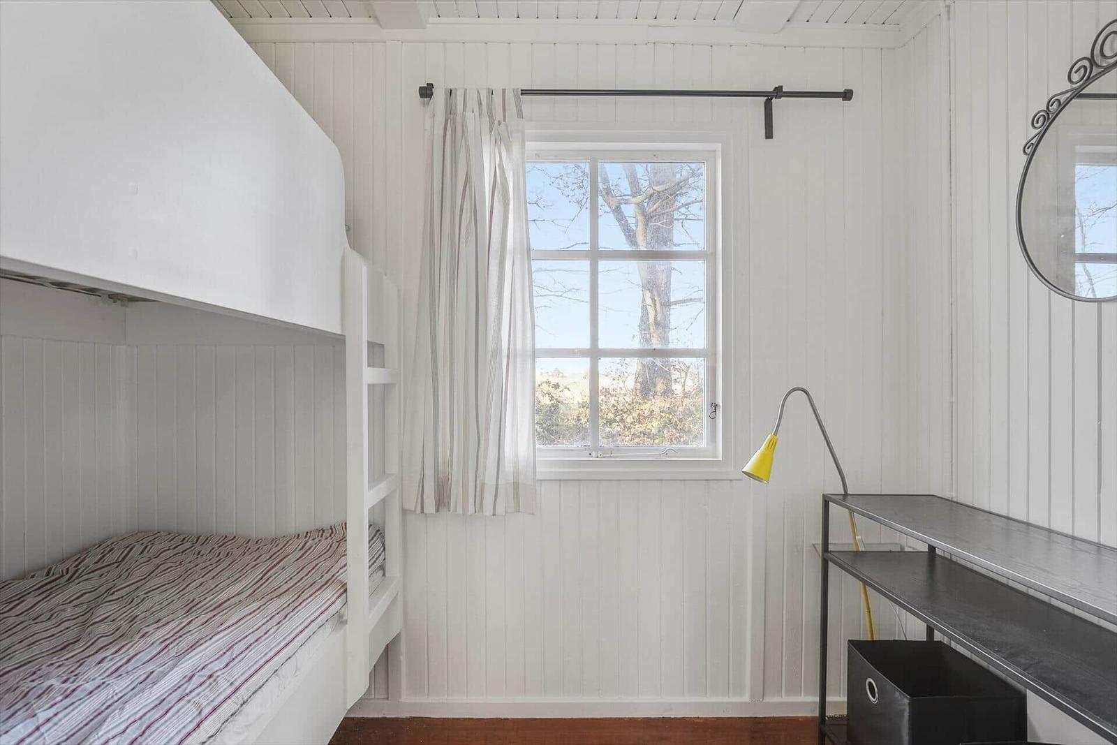 Zimmer mit Doppelstockbett, Fenster und Schreibtisch.