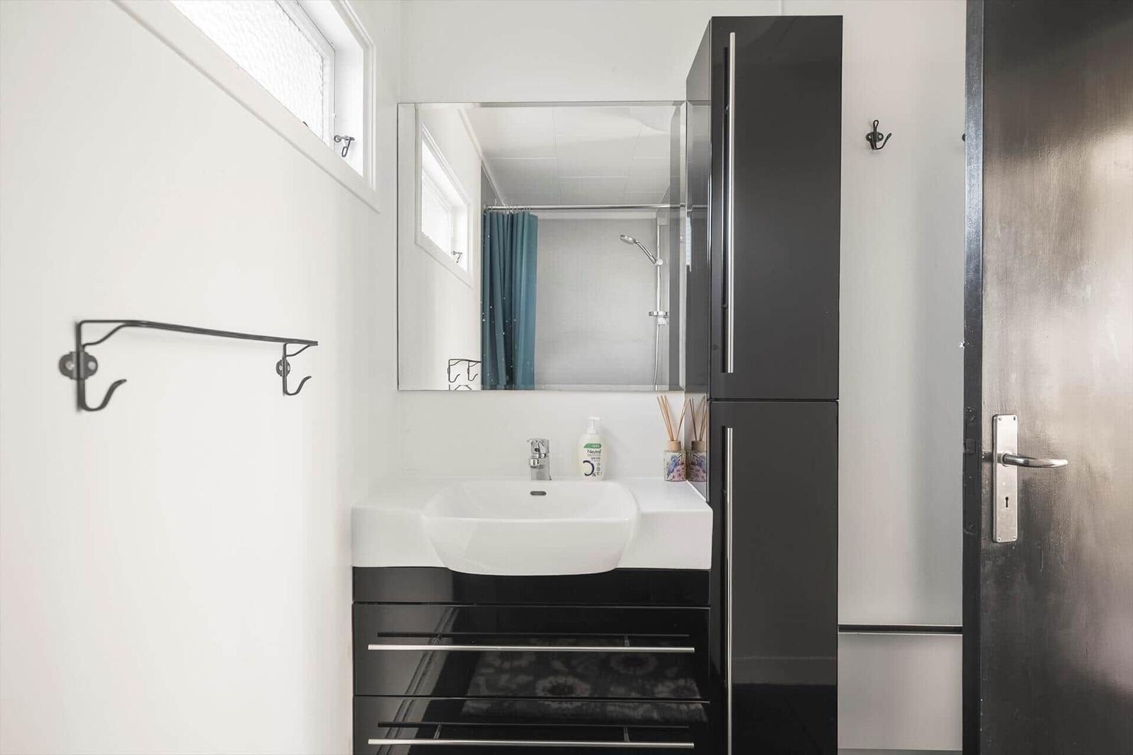 Badezimmer mit Waschbecken, Spiegel und Dusche