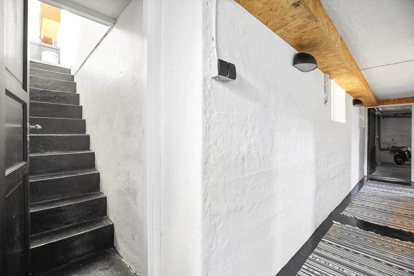 Halle mit Treppe, weißen Wänden und Holzbalken an der Decke.