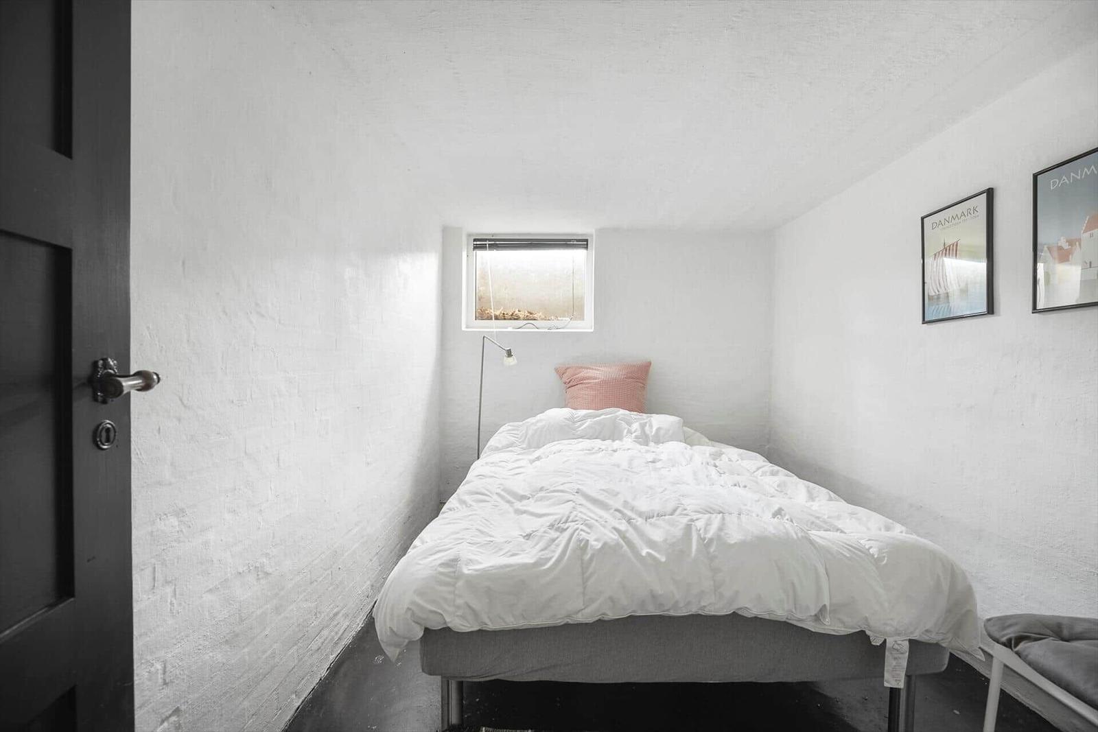 Schlafzimmer mit Bett, Fenster und Wandbildern.