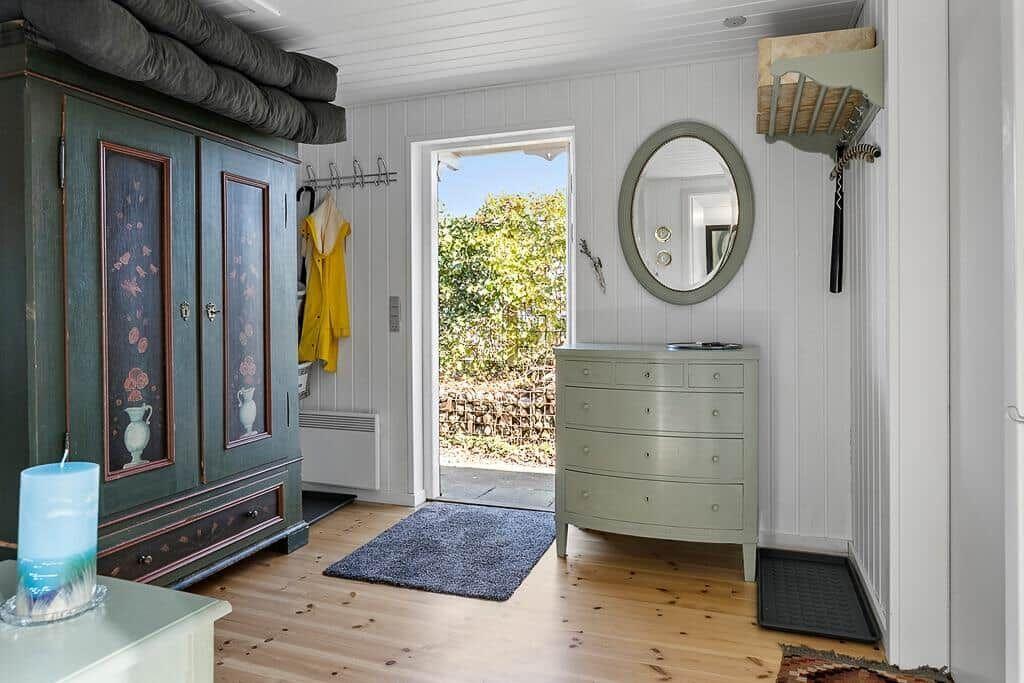 Schlafzimmer mit grünem Schrank, ovaler Spiegel und Holzboden.