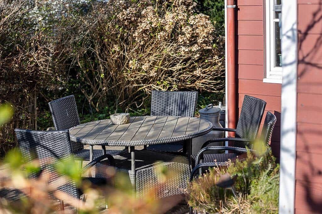Runder Tisch mit Stühlen im Garten neben rotem Haus