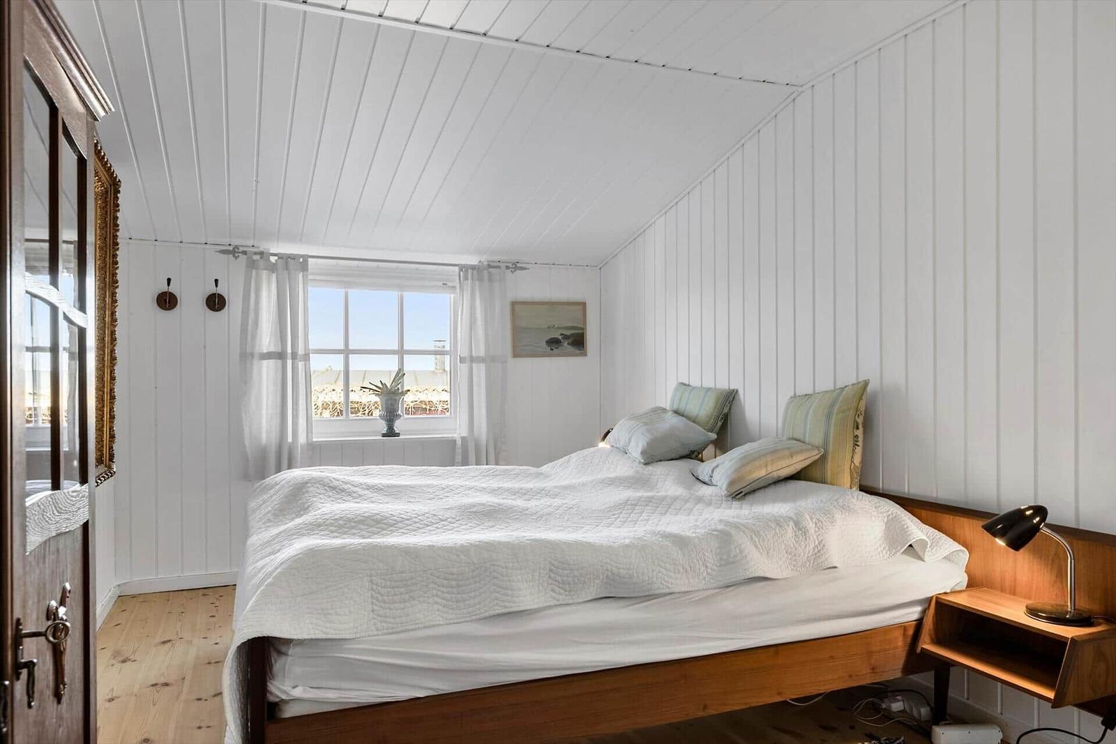 Schlafzimmer mit Bett, Fenster und Holzboden.