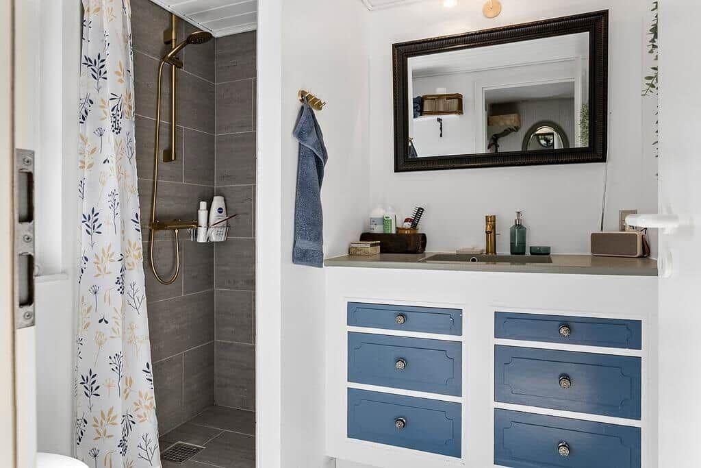 Badezimmer mit Dusche, Waschtisch und Spiegel.