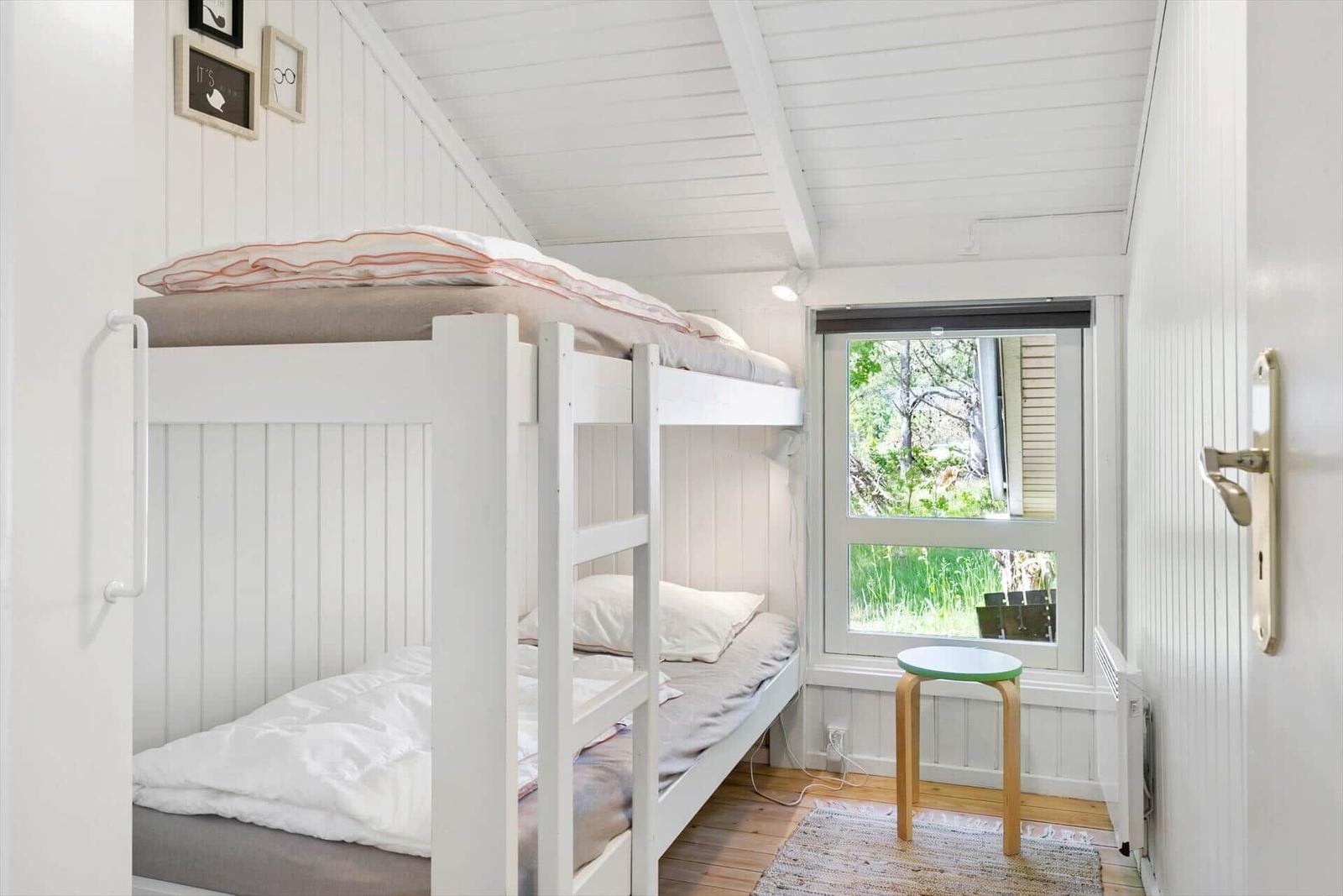 Zimmer mit Doppelstockbett, Fenster und Stuhl.