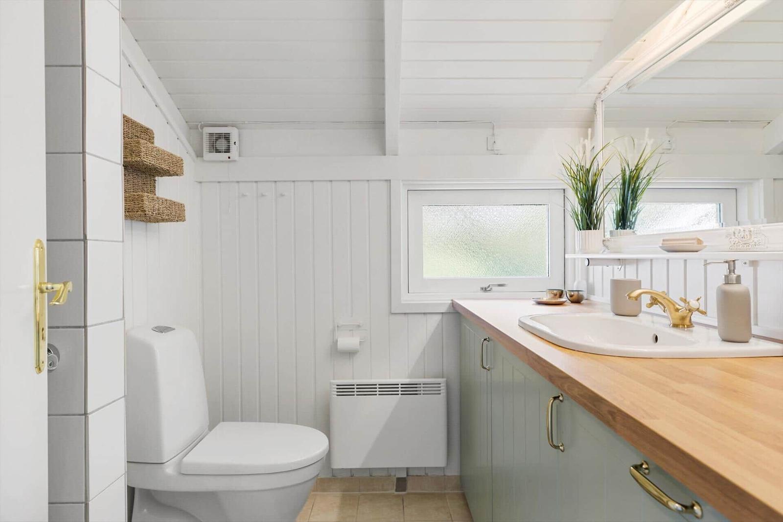 Badezimmer mit Toilette, Waschbecken und Fenster.