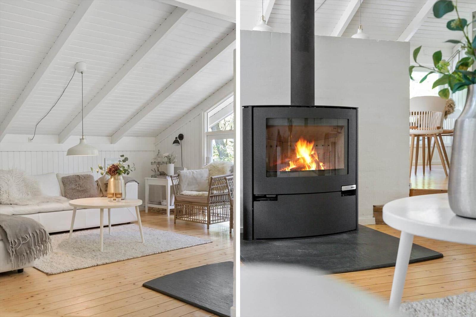 Wohnzimmer mit Kamin und Holzdielen. Weiße Wände und Dachschrägen.